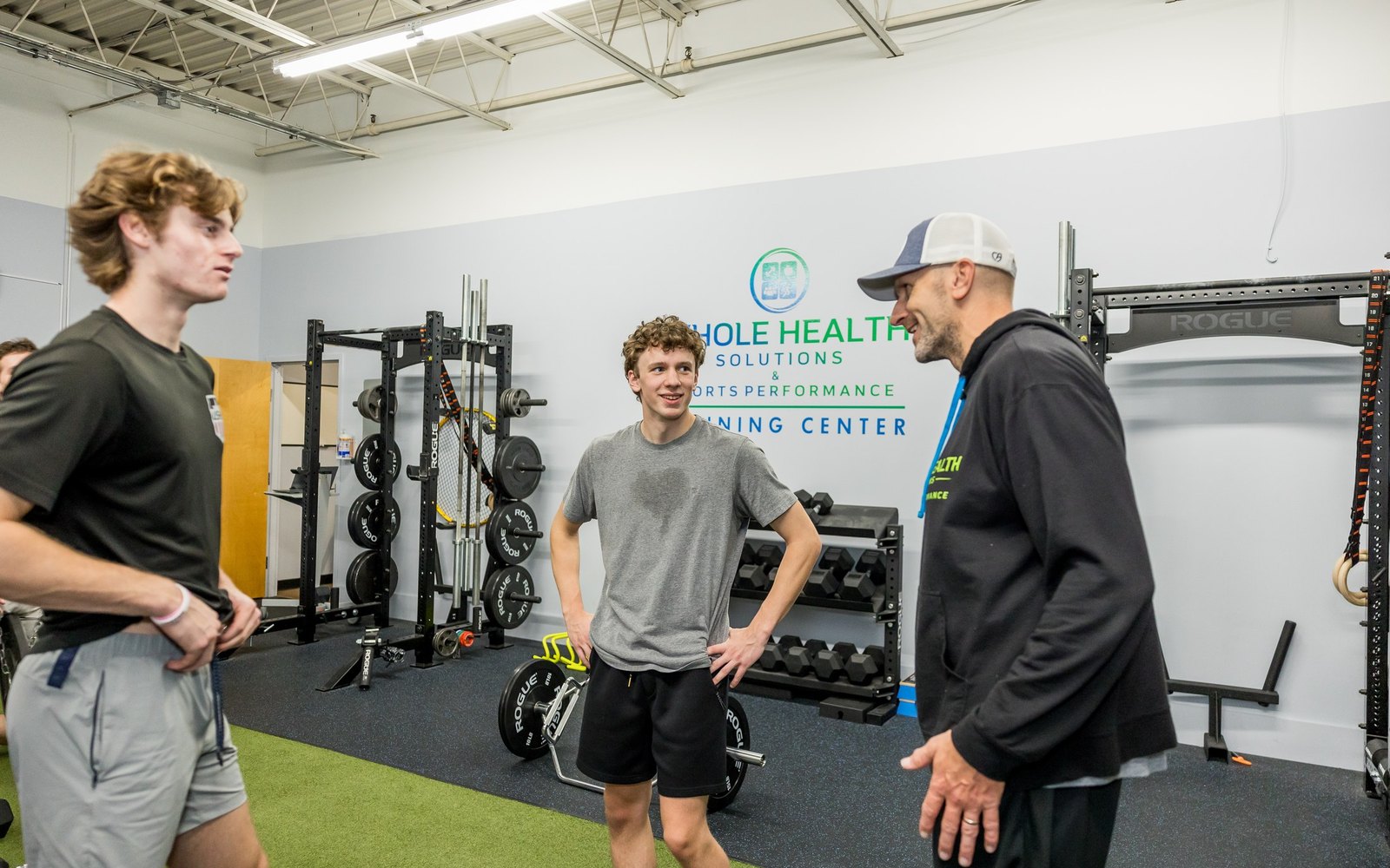 Coach chatting with two young athletes in the WHS training center