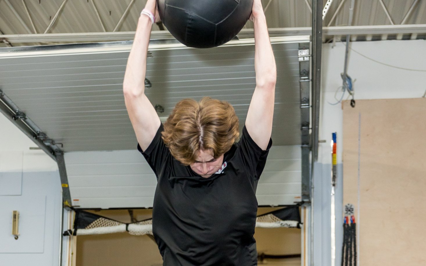 High school athlete doing a medicine ball slam during off season training