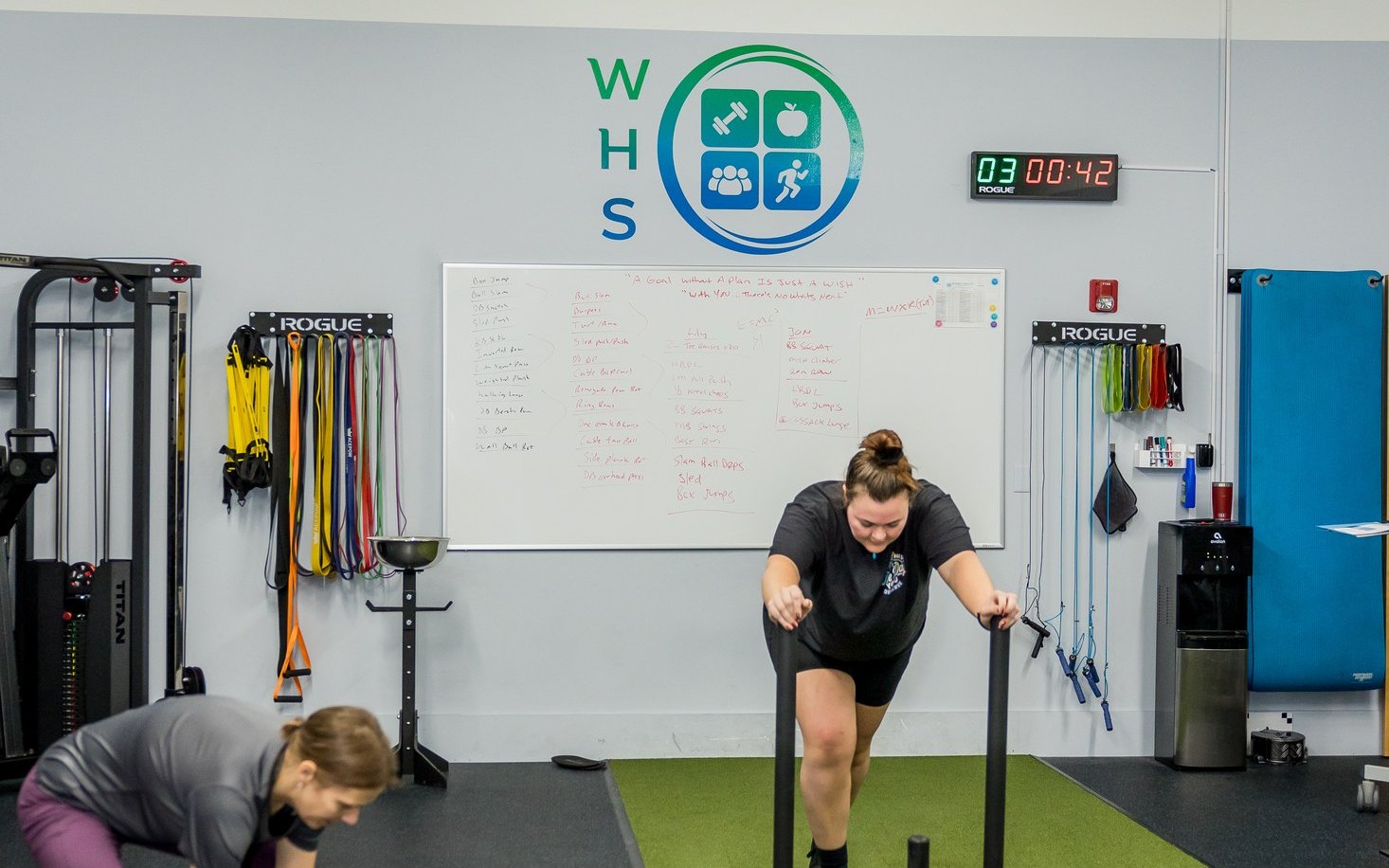 Athletes pushing a sled and lifting a medicine ball on the turf