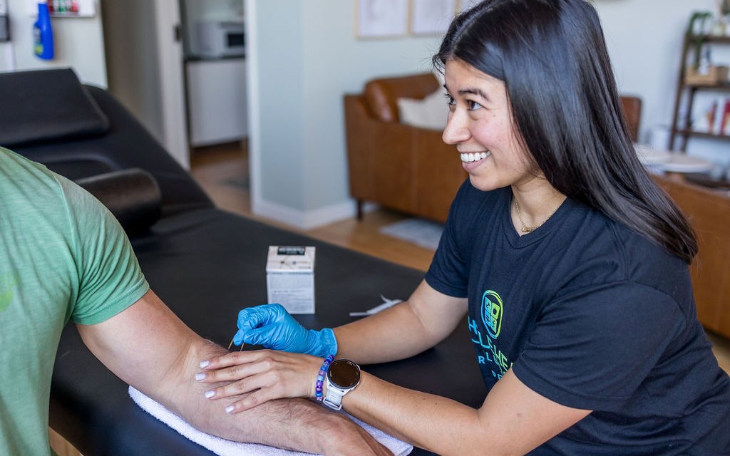 A physical therapist dry needling a client's forearm for elbow pain