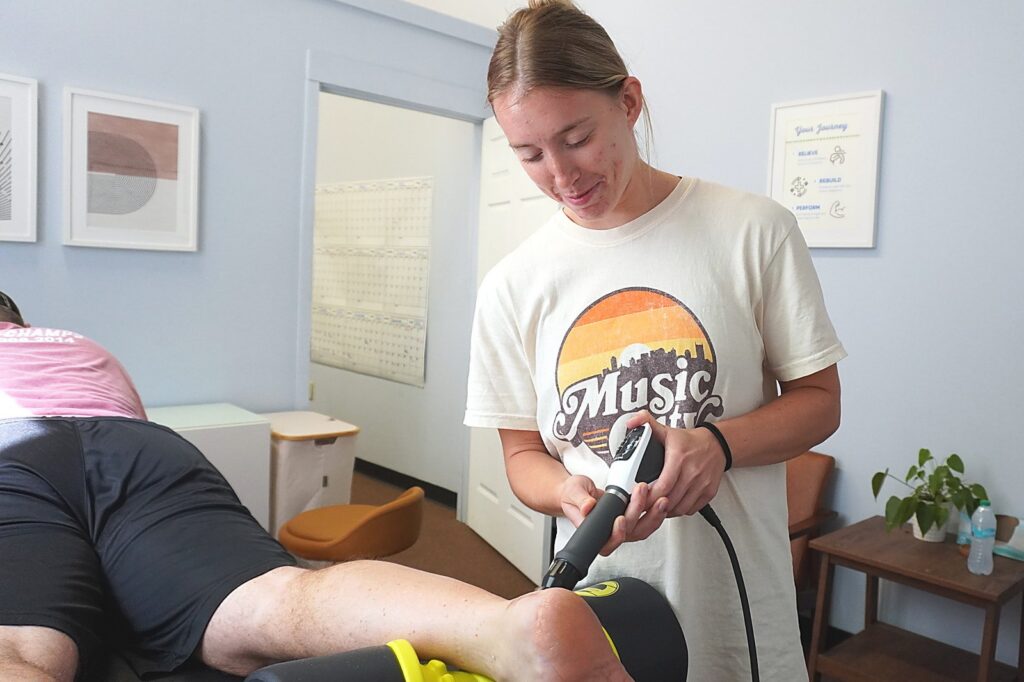 A physical therapist using shockwave therapy on a client's heel