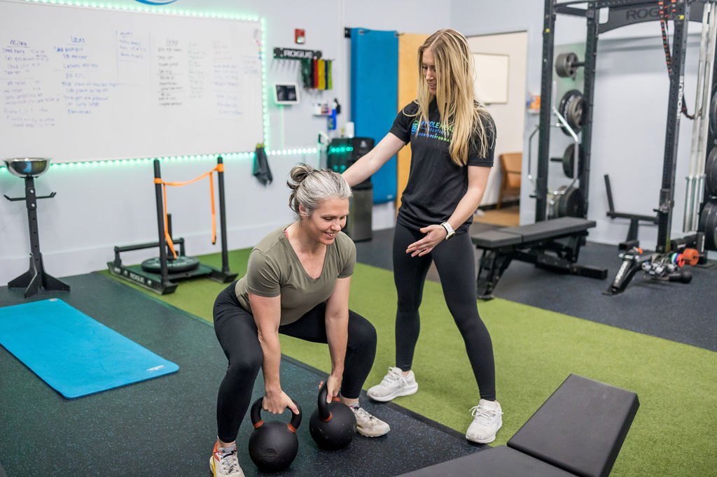 Personal trainer coaching a client through a kettlebell deadlift in the WHS training center in Shirley, MA