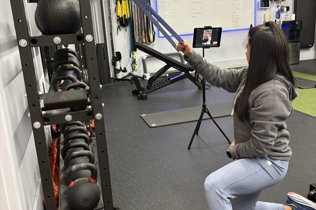 A client doing a live virtual training session with her Whole Health Solutions coach on a phone