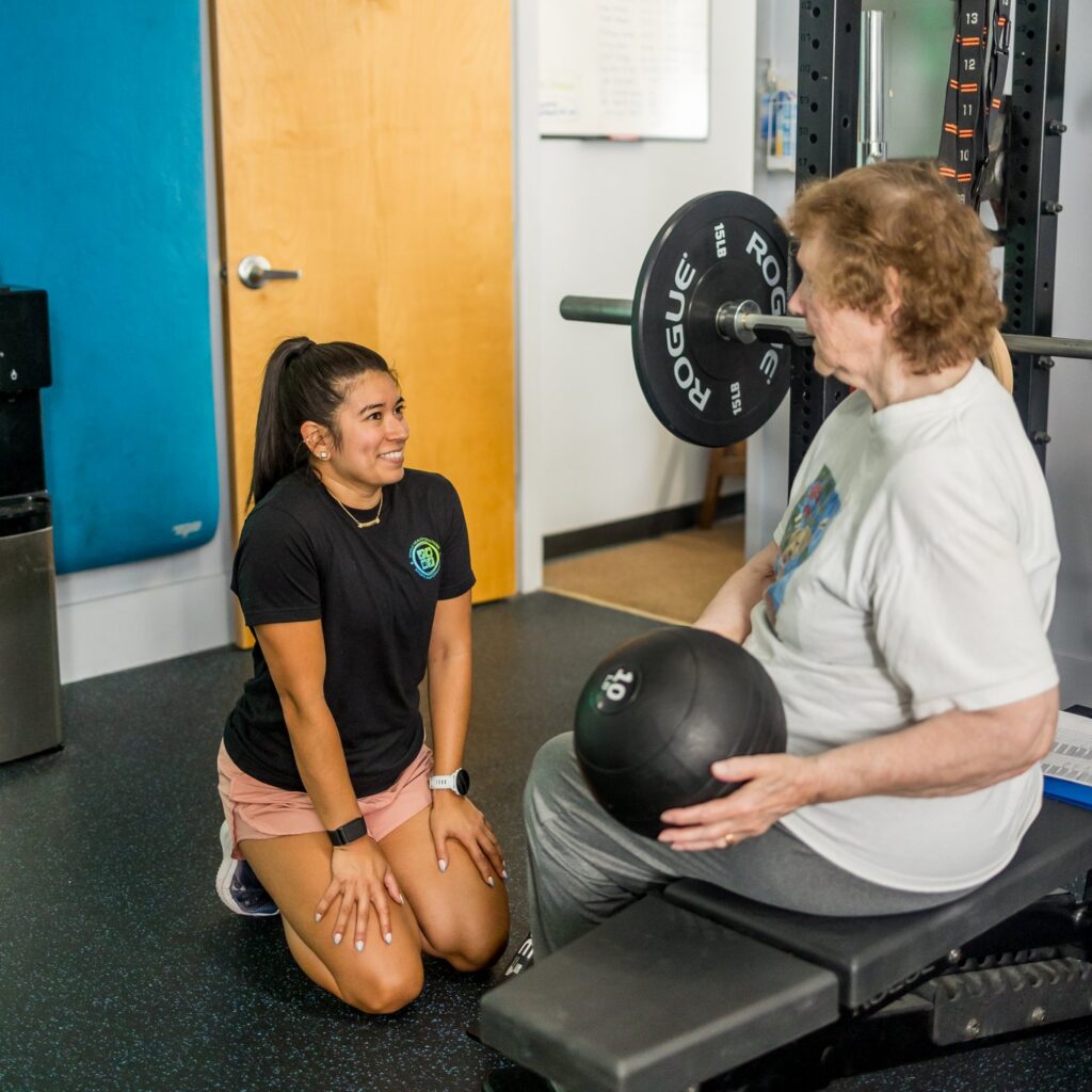 A physical therapist coaching an older client through a strength exercise at Whole Health Solutions