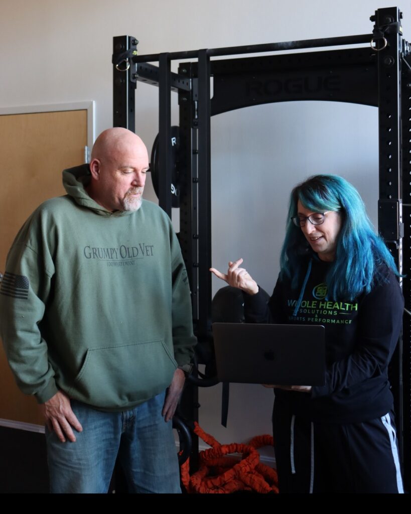 Health coach Christine going over a client plan on her laptop in the training center