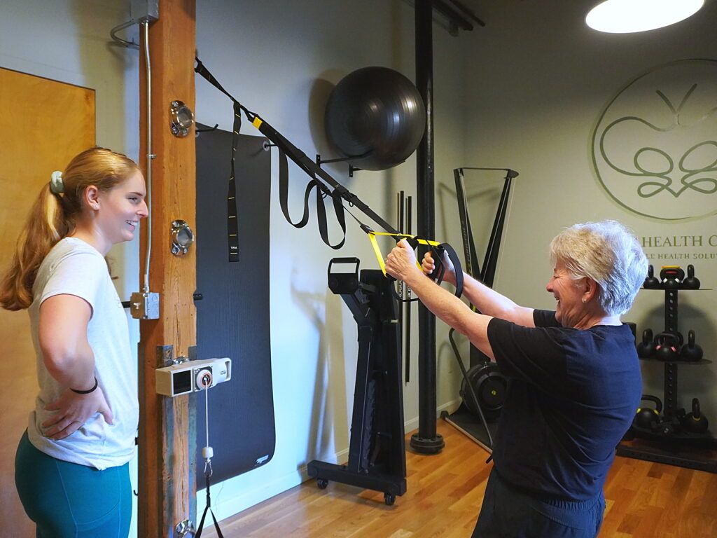 Pelvic floor physical therapist Dr. Caitlin McCutcheon coaching a client through a TRX squat in the Pelvic Health Center gym
