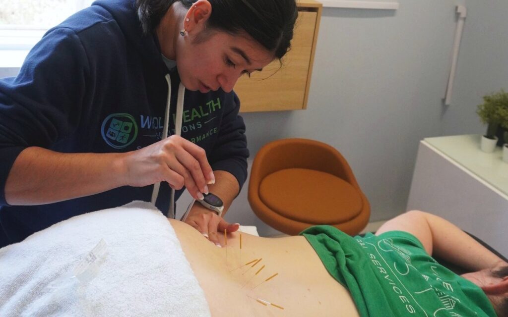 A physical therapist dry needling a client's low back at Whole Health Solutions