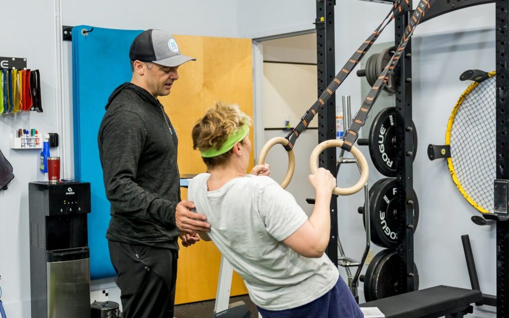 A physical therapist coaching posture and upper back strength with a ring row