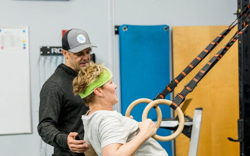 A physical therapist coaching a client through a ring row for upper back and neck strength
