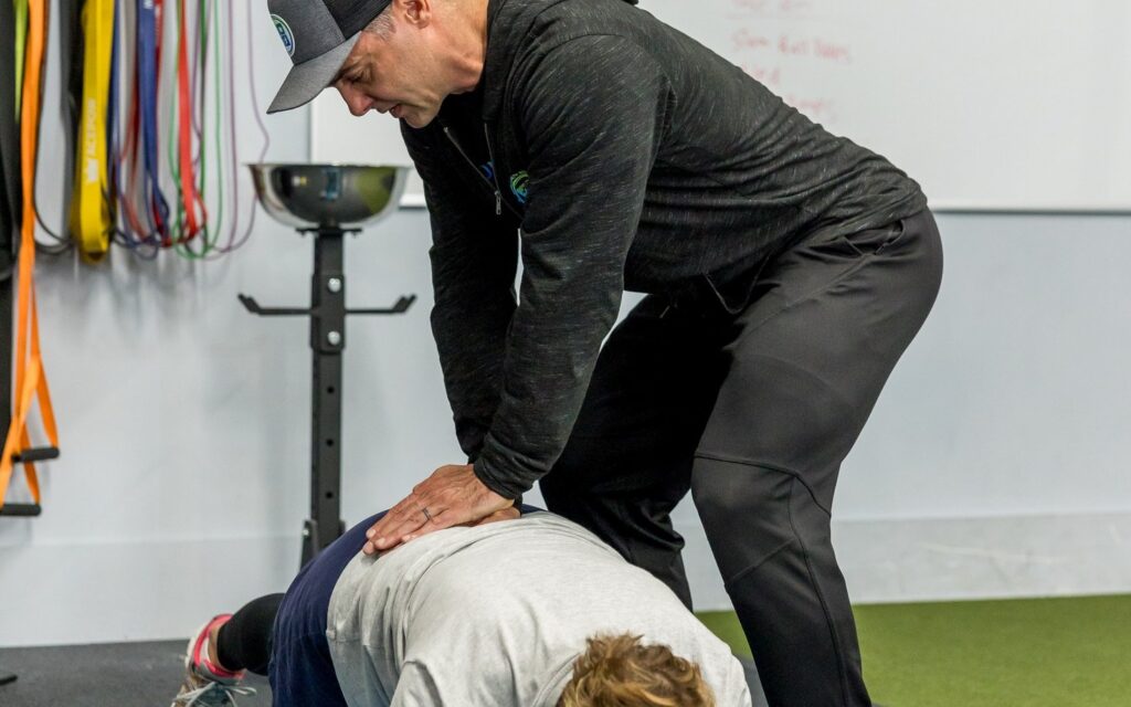 A physical therapist guiding a client's low back position during a core exercise