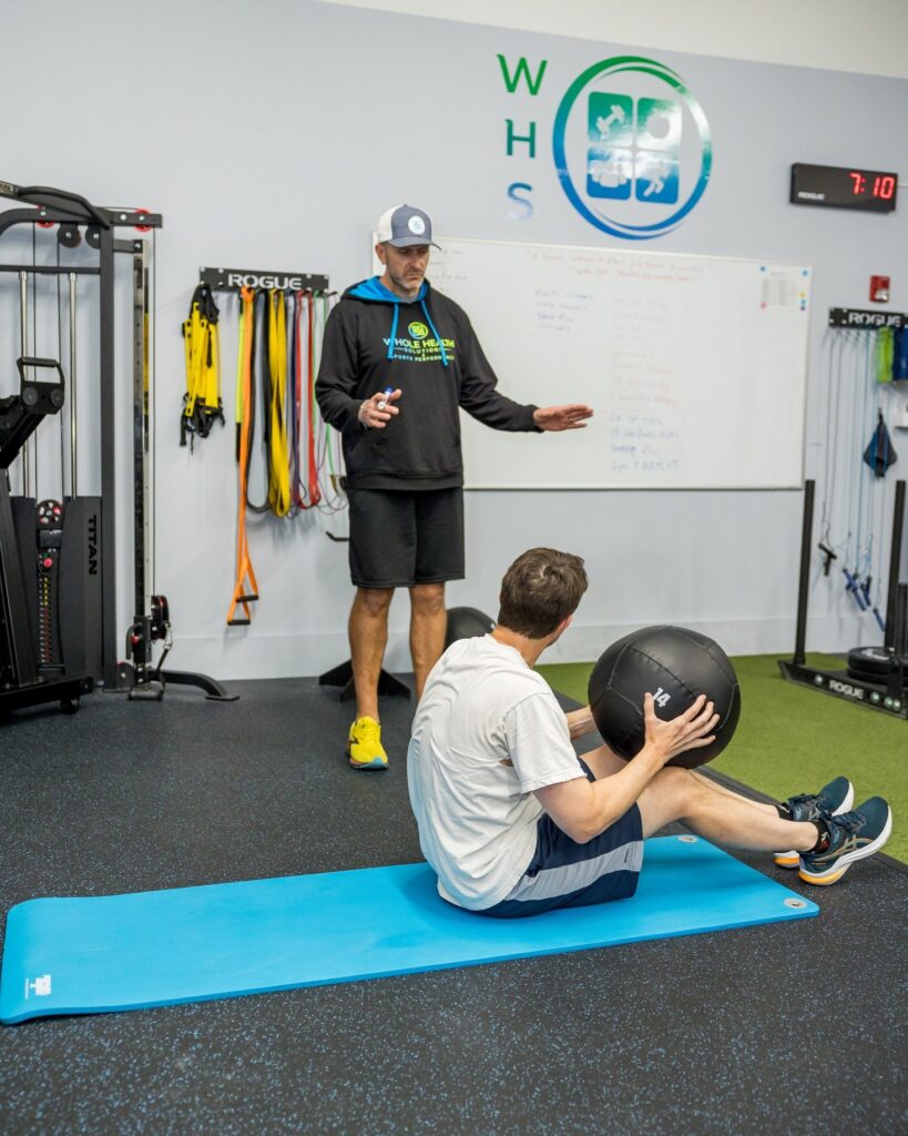 Physical therapist coaching a client through a seated exercise in the WHS clinic