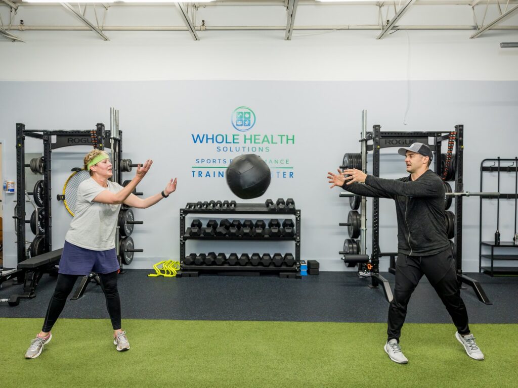 Coach and client tossing a medicine ball in the Whole Health Solutions training center